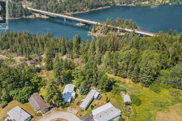 Aerial view showing the mobile home community near a large lake and bridge, surrounded by forest. - 2917 Georama Road Unit# 18, Nelson