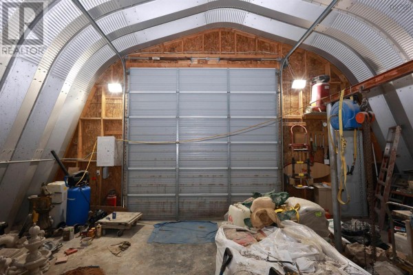 Exterior of a Quonset hut building with wood shingle siding and a large roll-up door. - 292 Sambro Creek Road, Sambro Creek