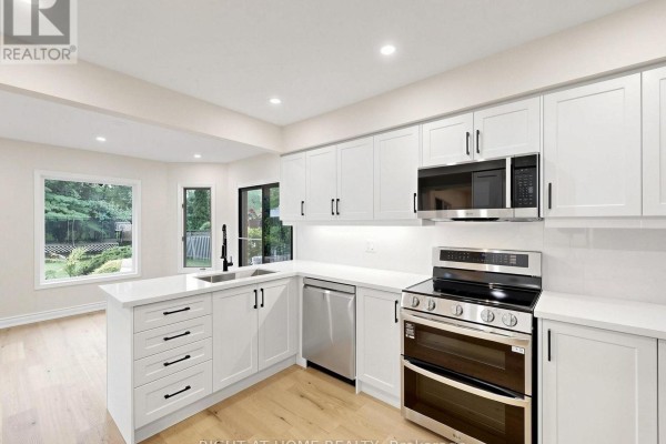 Modern kitchen with white cabinets, stainless steel appliances, and island - 2920 Kingsway Drive Oakville