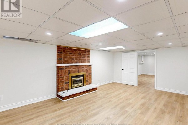 Brick fireplace and laminate flooring in basement living room - 2920 Kingsway Drive Oakville