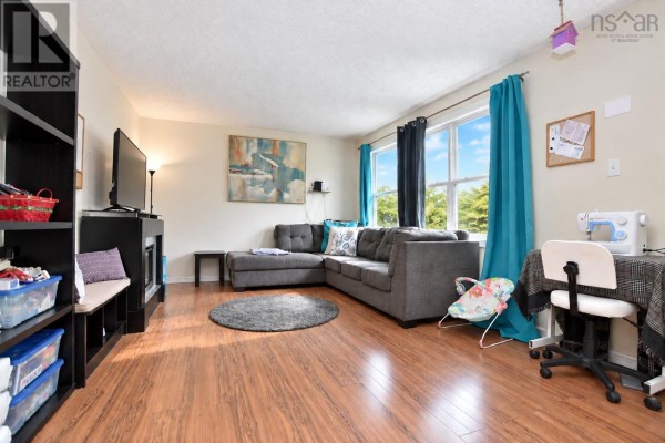 Living room with a grey sectional sofa, wood laminate flooring, a television, and storage shelves. - 2925 No. 7 Hwy, Lake Echo