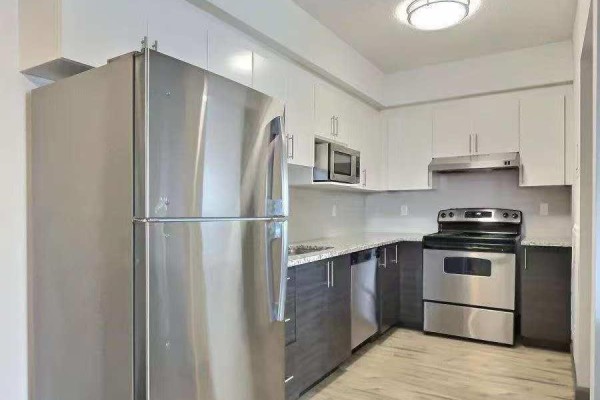Galley kitchen with stainless steel appliances, white and dark grey cabinets, and granite countertops. - 293 - 258b Sunview Street, Waterloo