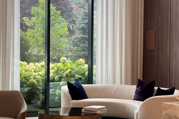 Living room with curved white sofa, velvet pillows, and large window overlooking garden. - 293 The Kingsway, Toronto