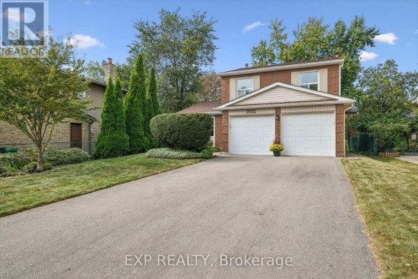 Side angle view of the brick house with a wide driveway and lush green landscaping. - 2932 Inlake Court, Mississauga