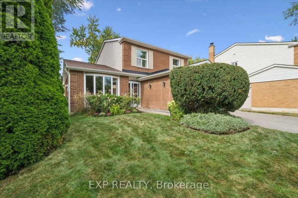 Close-up view of the brick house exterior with a bay window and flowering bushes. - 2932 Inlake Court, Mississauga