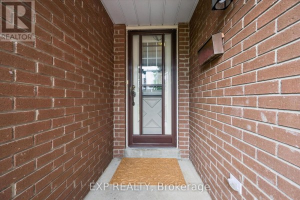 View of the front door from a covered porch, showing brick walls and a mail slot. - 2932 Inlake Court, Mississauga