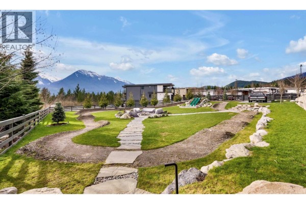 Landscaped backyard with pathways and seating area, buildings in the background. - 2934 Huckleberry Drive, Squamish