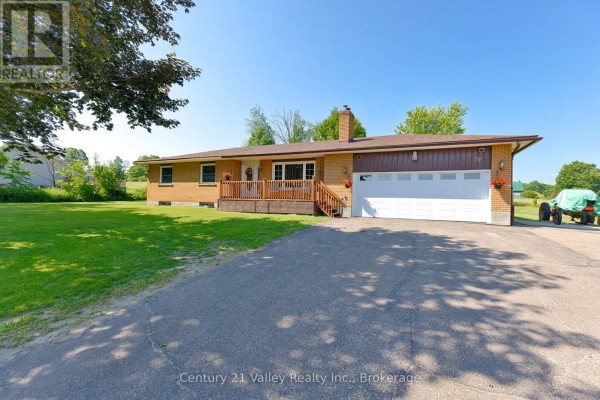Driveway leading to a brick ranch-style house with mature trees and a wide lawn. - 2935 Burnstown Road, Horton
