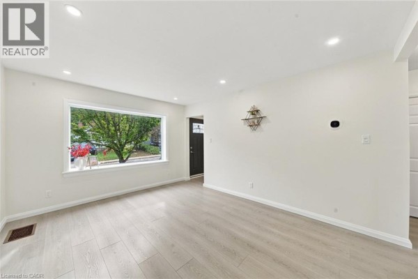 Living room with large picture window, recessed lighting, and light wood laminate flooring. - 294 East 28th Street, Hamilton