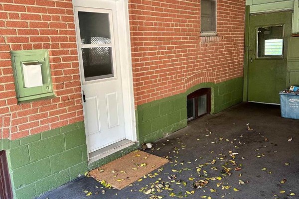 Exterior brick wall with a white door, green painted foundation, and green door. - 294 Felan Avenue, Oakville