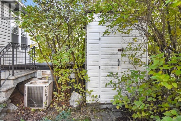 White storage shed in the backyard next to an air conditioning unit. - 294 Kathleen Street, Sudbury