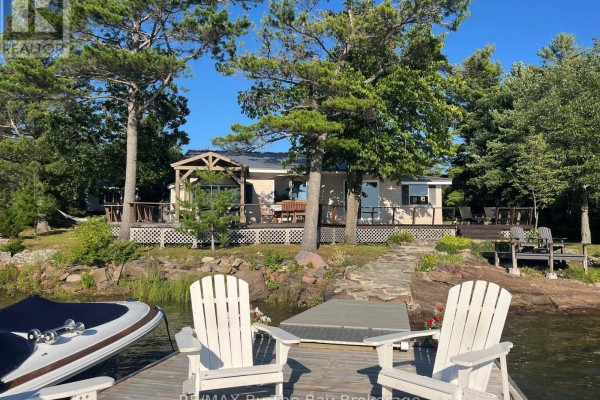 Outdoor seating arrangement with chairs around a stone fire pit on a grassy area near the lake. - 294 Prisque Road, Georgian Bay