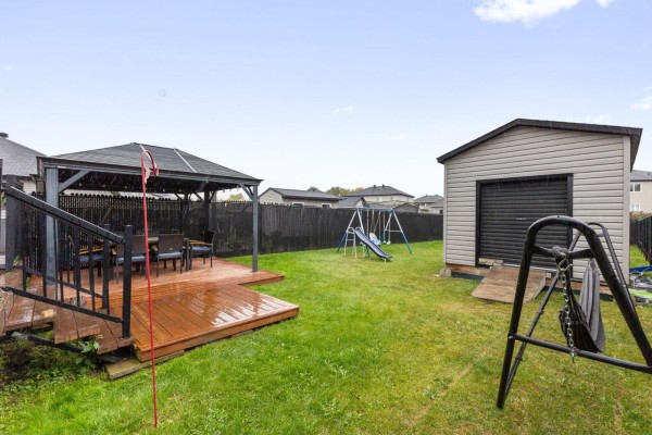 Backyard with a wooden deck, gazebo with table and chairs, shed, and children's swing set. - 294 Rue Des Becs-scie, Gatineau