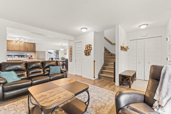 Living room with a leather sofa, recliner, coffee table, and a view of the kitchen and dining area. - 294 Rue Des Becs-scie, Gatineau