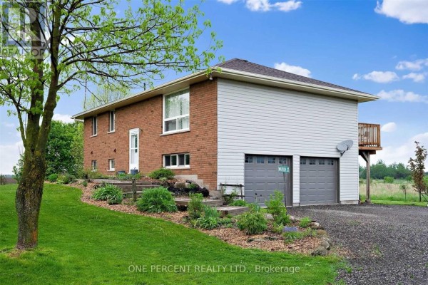 Side view of a two-story house with a brick lower level and vinyl siding upper level, featuring a double garage. - 294235 8th Line, Amaranth
