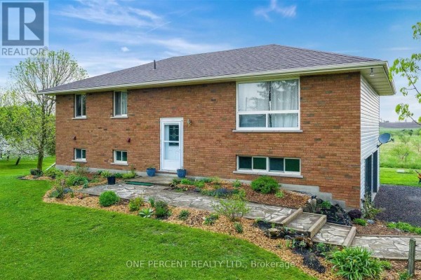 Front view of a brick house with a stone walkway leading to the front door and landscaping. - 294235 8th Line, Amaranth