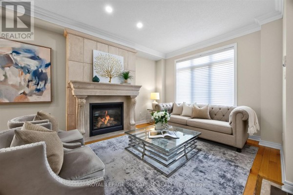 Living room featuring a stone fireplace, sofa, armchairs, and a large modern painting on the wall. - 2948 Bur Oak Avenue, Markham