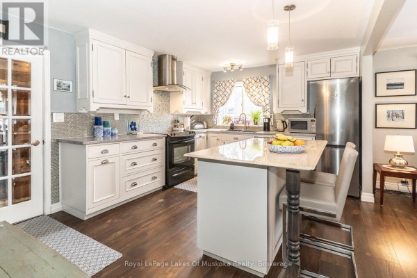 Open-concept living and dining area adjacent to the kitchen with neutral furniture. - 295 Bishop Street, Gravenhurst)