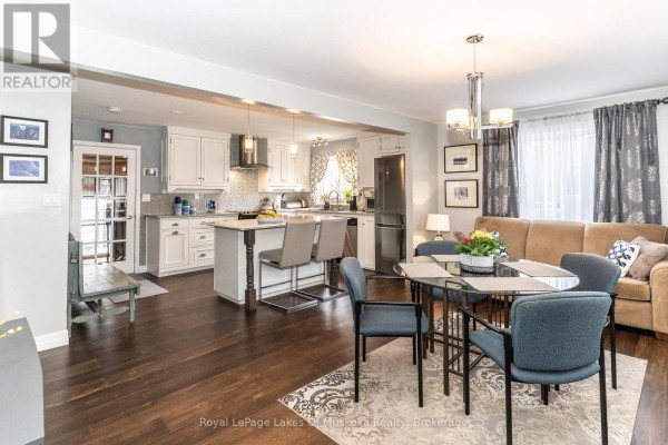 Dining area with a glass table and blue chairs, connected to the kitchen. - 295 Bishop Street, Gravenhurst)