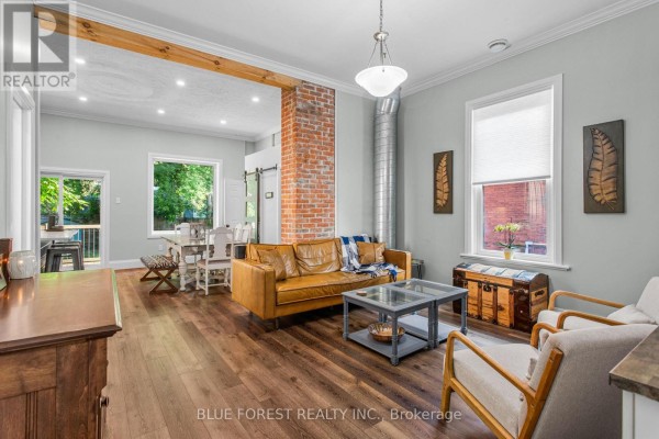 Living room with a brown leather sofa, glass coffee table, and chairs. - 295 Buller Street, Woodstock