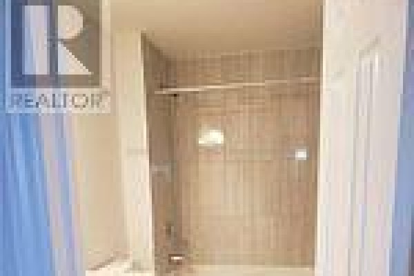 Interior of a bathroom with tiled walls, a shower rod, and a closed door. - 2954 Turner Crescent, London South