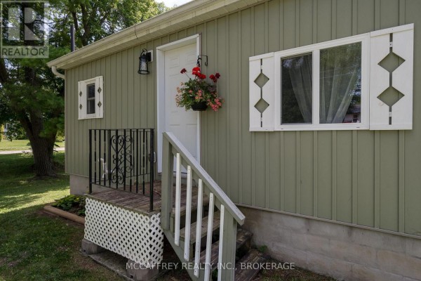 Close-up of the entrance to the light green house, showing steps and white shutters. - 2956 County Road 14, Stone Mills
