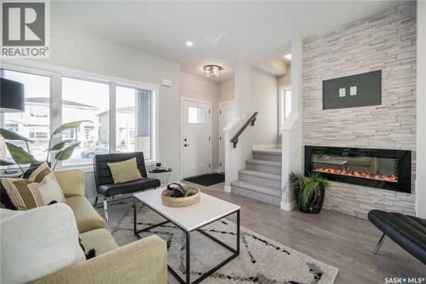 Entryway with a black front door, stairs, and a stone-clad gas fireplace. - 2956 Green Turtle Road, Regina