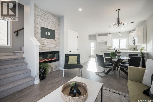 Living area with a large window, view of the fireplace, entryway, and kitchen. - 2956 Green Turtle Road, Regina