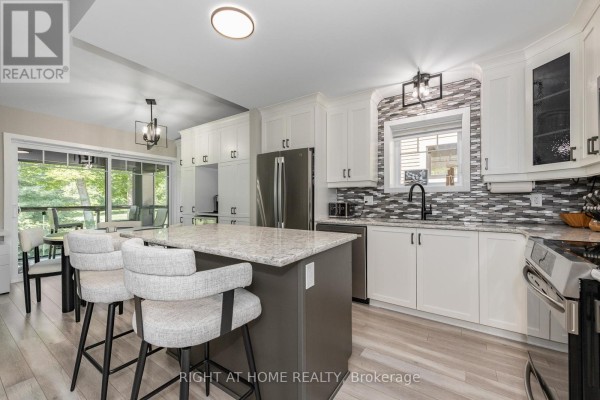 Kitchen with white cabinets, granite island, stainless steel appliances, and tiled backsplash. - 296 - 308 Masters Lane, Clarence Rockland
