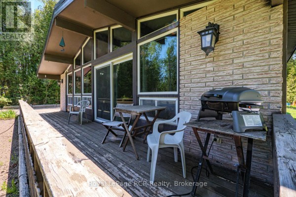 Deck with two small tables, chairs, and a barbecue, attached to a house with large windows. - 296 Bryant Street, South Bruce Peninsula