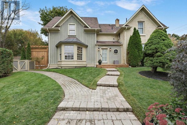 View of the front of a house with brick and siding, featuring a bay window and stone pathways. - 296 Eagle Street, Newmarket