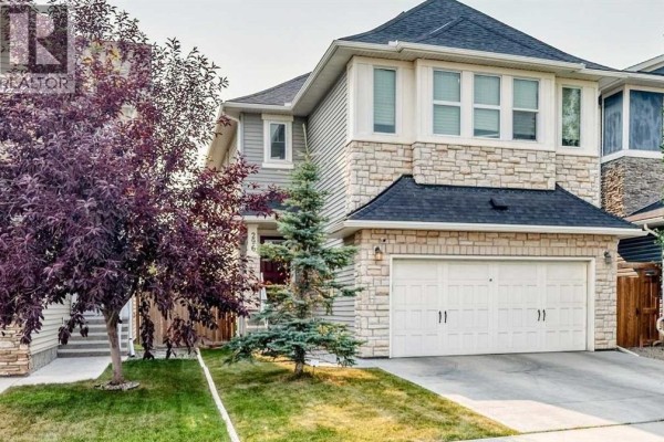 Front exterior view of a two-story house showcasing stone and vinyl siding and a double garage door. - 296 Nolancrest Heights Nw, Calgary