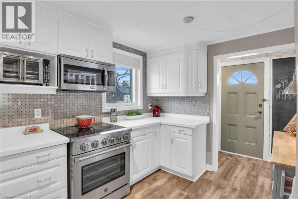 Kitchen with white cabinets, stainless steel appliances, and a window overlooking the backyard. - 296 Weber Street E, Kitchener