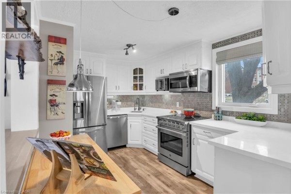Kitchen with white cabinets, stainless steel appliances, and a view of the dining area. - 296 Weber Street E, Kitchener