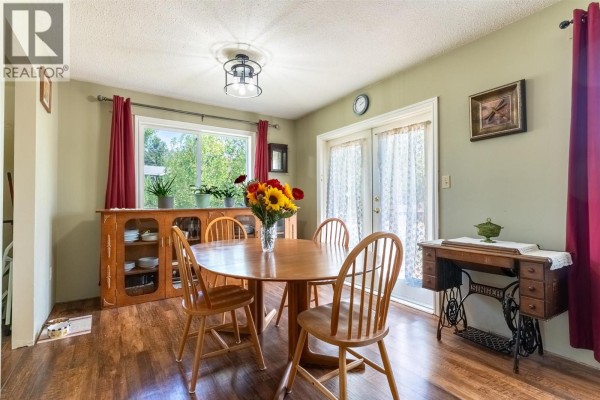 Dining room with a wooden table and chairs, buffet, and French doors leading outside. - 297 Chestnut Court, Logan Lake