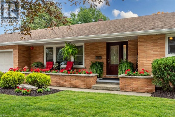 Close-up of the front entrance of a brick house with a covered porch and decorative planters. - 297 Main Street W, Otterville