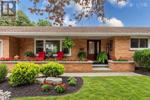 Front view of the house entrance with a dark red door, windows, and stone planter boxes. - 297 Main Street W, Otterville
