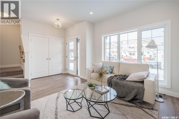 Kitchen with white cabinets, grey tile backsplash, and stainless steel microwave, showing countertop and sink. - 2972 Green Turtle Road, Regina