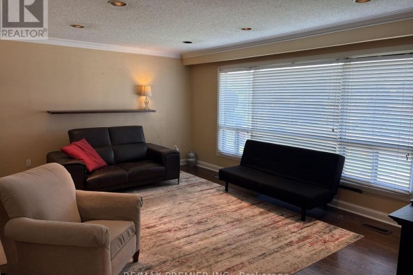 Living room with dark leather sofa, armchair, futon, and large window with blinds. - 2979 Weston Road, Toronto