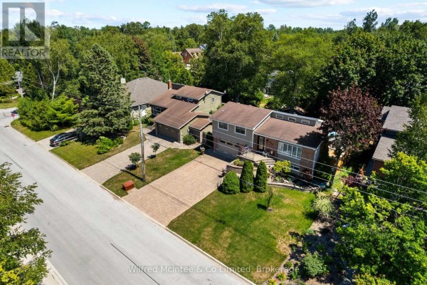 Backyard view showing a lawn, mature trees, and a partial view of the house. - 298 Albert Street S, Saugeen Shores