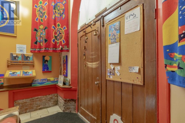 Interior entryway with wooden double doors, corkboard, artwork, and colorful hanging textiles. - 298 Granville Street, Bridgetown