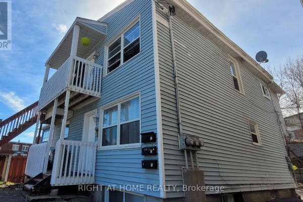 Side view of a light blue two-story multi-family home with an exterior staircase and parking. - 298 Montfort Street, Ottawa