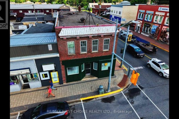 Aerial view of a brick building with green accents and nearby pedestrian. - 298 Scott Street, Fort Frances