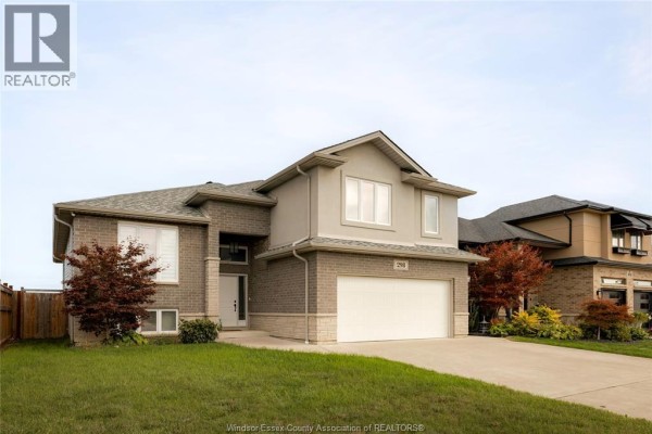 Exterior view of a contemporary house with brick and stucco facade, autumnal trees, and driveway. - 298 Welsh Avenue, Amherstburg