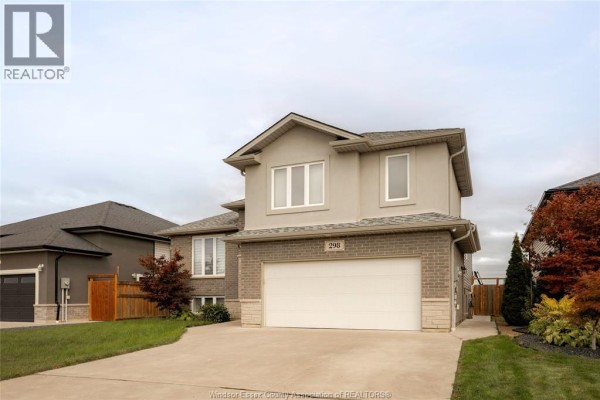 Side view of a two-story home with a large garage door and landscaping in the foreground. - 298 Welsh Avenue, Amherstburg