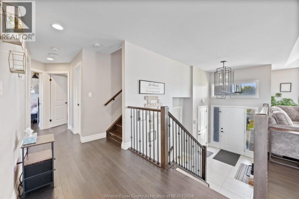 Spacious entryway with dark hardwood floors, a staircase with iron railings, and multiple doorways. - 298 Welsh Avenue, Amherstburg