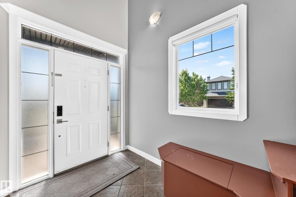 Interior entryway with a white front door, frosted glass sidelights, and a window view. - 2984 Mcphadden Wy Sw, Edmonton