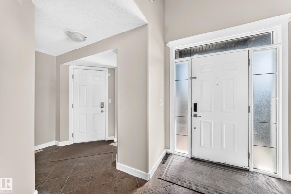 Interior entryway with a dark tiled floor and two white doors. - 2984 Mcphadden Wy Sw, Edmonton