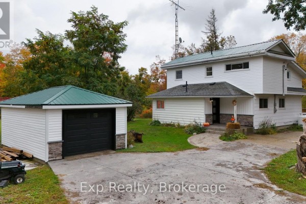 White house with a green metal roof and a detached garage with a black door. - 2988 County 44 Road, Havelock Belmont Methuen