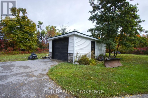 White detached garage with a green metal roof and a black door, parked beside a concrete driveway. - 2988 County 44 Road, Havelock Belmont Methuen